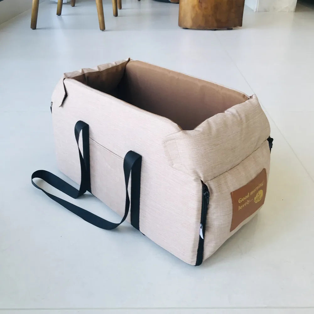 Beige pet carrier with black straps on a light gray floor