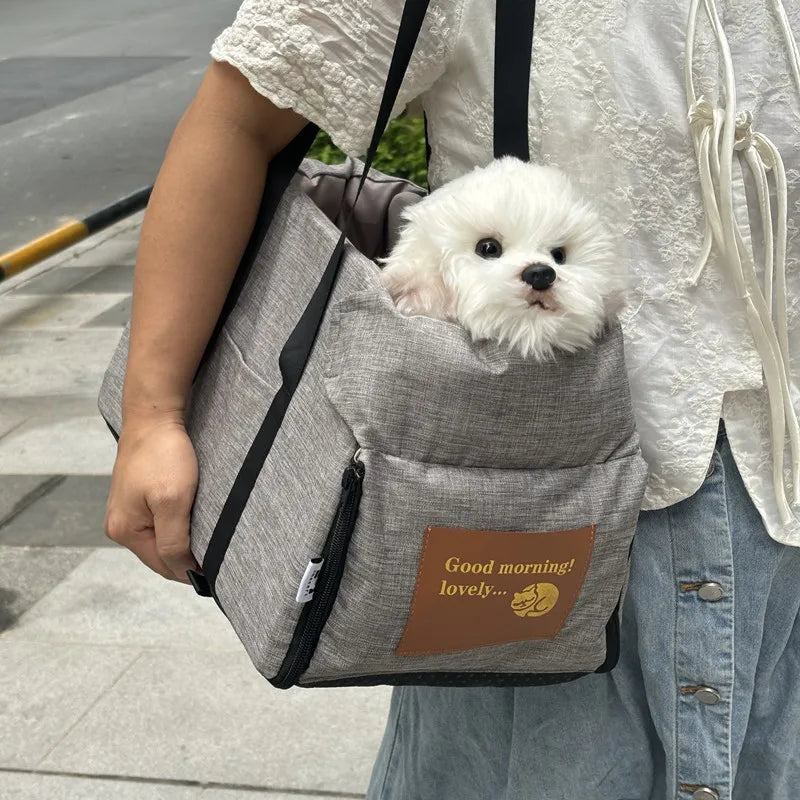 Small white dog in a gray pet carrier with 'Good morning! lovely...' text on a person's shoulder.
