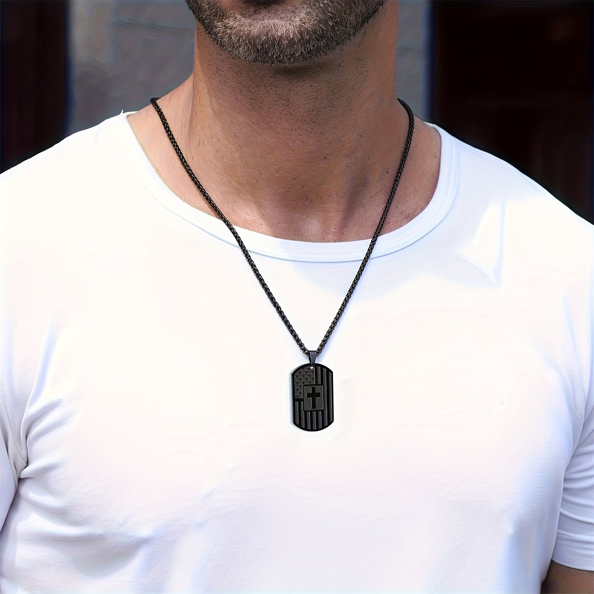 Man wearing a black necklace with a pendant on a white shirt